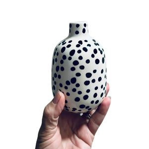 holding black and white polka dot vase